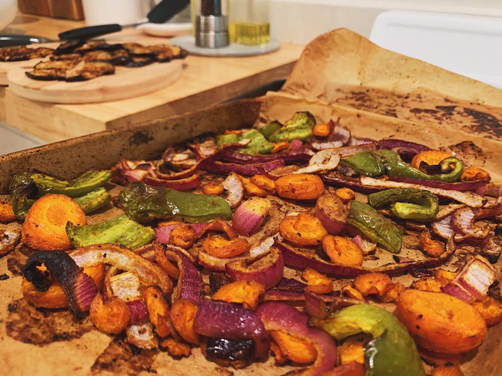 Roasted red onion, carrot, and green bell pepper with olive oil, salt, pepper, curry powder, smoked paprika, garlic powder, and onion powder on a parchment-lined baking sheet.